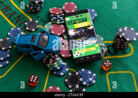 Kasino-Chips und Spielzeugauto, Smartphone mit Sportwetten Stockfoto