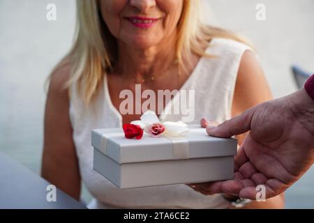 Nahaufnahme einer Seniorin, die von ihrem Mann ein liebevolles Geschenk für Valentinstag erhält Stockfoto