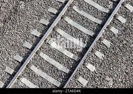 Hintergrundtextur für Eisenbahn. Stahlschienen auf grauen Betonschwellen über Kiesboden montiert. Fotomuster für den industriellen Transport Stockfoto