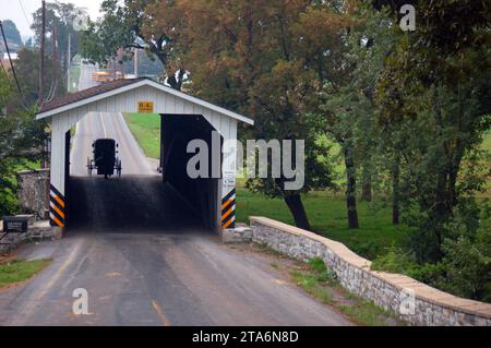 Ein Amish-Pferd und Buggy bereitet sich auf die Überquerung einer historischen überdachten Brücke im Pennsylvania Dutch Country im Lancaster County vor Stockfoto