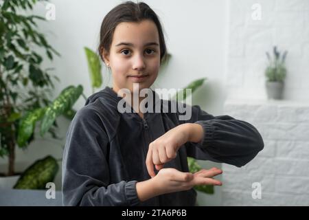 Wunderschönes, lächelndes, taubes Mädchen, das Gebärdensprache benutzt. Stockfoto