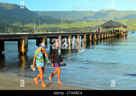 Ein erwachsenes Paar spaziert während ihres Urlaubs am Strand und genießt den Hanalei Pier auf Kauai, Hawaii Stockfoto