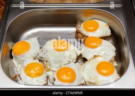 Rindersteaks mit Spiegelei auf Edelstahltablett. Spiegeleier mit Rinderschnitzel auf dem Hotelschmelzladen, auf der Theke des Kochens, auf dem Lebensmittelmarkt. Stockfoto