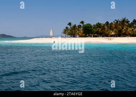 Palm Island Waters Edge View: Casuarina Beach, ruhiges türkisfarbenes Karibisches Meer, sanfte Wellen und Palmen mit fernen Grenadinen und blauem Himmel. Stockfoto