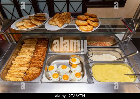 Fast Food Bistro, Essen in Metalltabletts, Schnitzel Salate am Fenster des Cafés, Patches mit Essen auf der Bistrotheke, Fleisch und Garnierung in Patches. Stockfoto