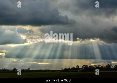 Sonnenstrahlen, die am späten Winternachmittag durch Sturmwolken leuchten - Zentralfrankreich. Stockfoto