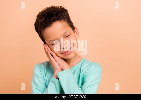 Foto des charmanten träumenden Jungen Sohn tragen trendige Kleidung Pyjama schlafen genießen Relax Rest Haus isoliert auf beigefarbenem Hintergrund Stockfoto