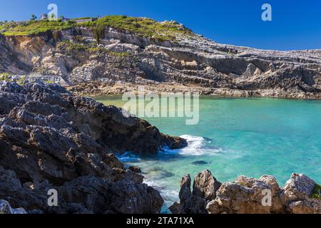 Azurblaue Gewässer des Atlantischen Ozeans, umgeben von Klippen in der Stadtbucht. Sommer, sonniger Tag. Llanes, Asturien, Spanien. Stockfoto