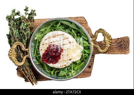 Gebackener Camembert-Brie-Käse mit Preiselbeersauce und garniert mit Rucola-Salat in einer Pfanne. Isolierter, weißer Hintergrund Stockfoto