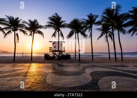Palmen und Rettungsschwimmerposten am Copacabana Beach am Sonnenaufgang und berühmtem Bürgersteig Mosaic Stockfoto