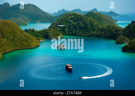 Flugzeug fliegt über einem Tourboot und Schnellboot in einer tropischen Lagune, Wayag, Raja Ampat, West Papua, Indonesien Stockfoto