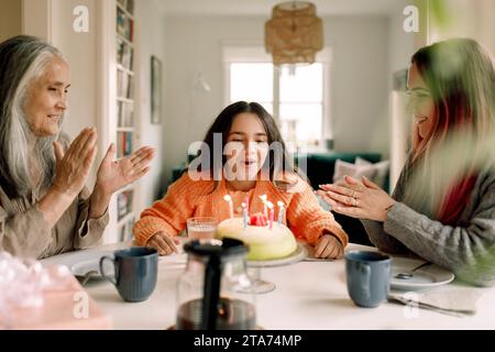 Fröhliches Mädchen feiert Geburtstag mit Mutter und Großmutter zu Hause Stockfoto