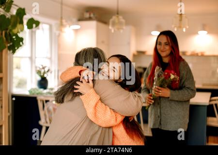 Glückliches Mädchen, das Großmutter umschließt und zu Hause grüßt Stockfoto