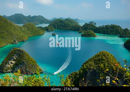 Schnellboot, das an einem Tourboot in einer tropischen Lagune vorbeisegelt, Wayag, Raja Ampat, West Papua, Indonesien Stockfoto