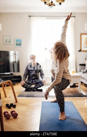 Ältere Frau, die sich beim Yoga auf der Trainingsmatte zu Hause dehnt Stockfoto