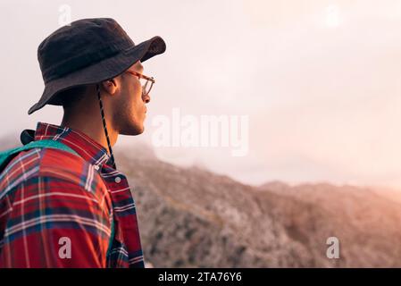 Seitenansicht eines Mannes, der Hut trägt und den Sonnenuntergang im Urlaub bewundert Stockfoto