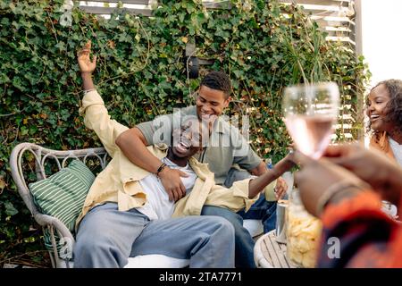 Fröhlicher junger Mann, der mit Freunden beim Feiern während der Dinnerparty genießt Stockfoto