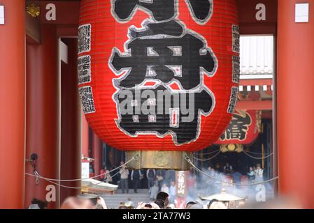 Eine Nahaufnahme der legendären riesigen roten Laterne am Eingang des Senso-JI-Tempels in Asakusa, Tokio, mit Besuchermassen im Hintergrund Stockfoto