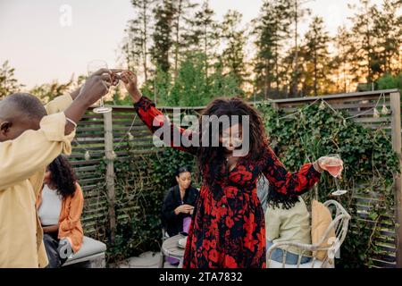 Männliche und weibliche Freunde tanzen zusammen während der Feier auf der Dinnerparty im Hinterhof Stockfoto