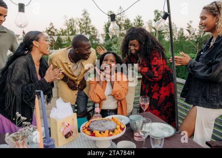 Fröhliche junge Männer und Frauen feiern den Geburtstag einer Freundin im Hinterhof Stockfoto