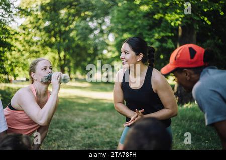 Begeisterte Coach, die während des Trainings im Park mit dem Team diskutiert Stockfoto