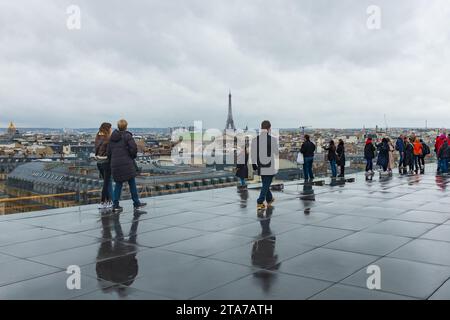 Paris, Frankreich, 2023. Besucher genießen die Aussicht von der Dachterrasse der Galeries Lafayette an einem regnerischen Tag mit dem Eiffelturm im Hintergrund Stockfoto