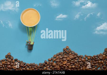 Abstrakter Heißluftballon aus Espresso Cup und Miniature People. Berge aus Kaffeebohnen Stockfoto