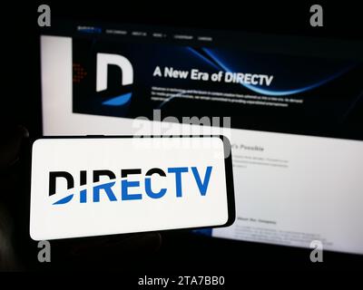 Person, die ein Smartphone mit dem Logo des US-amerikanischen Fernsehverteilers DirecTV LLC vor der Website hält. Schwerpunkt auf dem Display des Telefons. Stockfoto