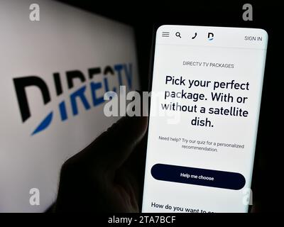 Person mit Mobiltelefon und Website des US-amerikanischen Fernsehverteilers DirecTV LLC vor dem Logo. Konzentrieren Sie sich auf die Mitte des Telefondisplays. Stockfoto