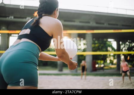 Eine Frau serviert Volleyball, während sie mit einem Freund spielt Stockfoto