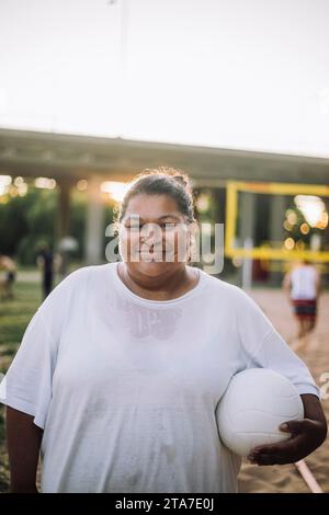 Porträt einer lächelnden übergroßen Frau mit weißem T-Shirt und Volleyball Stockfoto