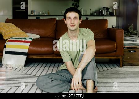 Porträt eines jungen Mannes, der zu Hause auf dem Boden sitzt Stockfoto