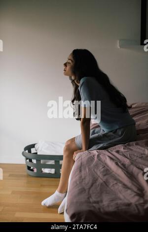 Deprimierte Frau, die zu Hause auf dem Bett sitzt Stockfoto
