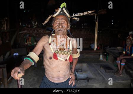 Portarit eines Ältesten, ein Mann aus einem Konyak-Stamm mit traditionellen Stammes-Tattoos auf seinem Gesicht und traditionellem Hut, Nacken, Ohrringen, Nagaland, Indien Stockfoto