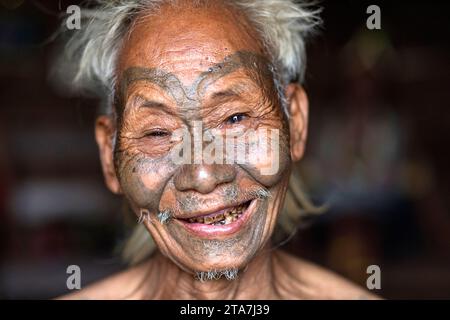 Portarit eines Ältesten, ein Mann aus einem Konyak-Stamm mit traditionellen Stammestattoos im Gesicht, lächelnd in der Kamera, Nagaland, Indien Stockfoto