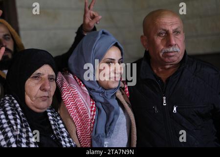 (231129) -- GAZA, 29. November 2023 (Xinhua) -- Ein freigelassener palästinensischer Gefangener (C) vereinigt sich mit Familienmitgliedern im Dorf Dura, südlich der Westjordanstadt Hebron, 29. November 2023. Die israelische Regierung bestätigte am Dienstag, dass die fünfte Reihe von Geiseln, die von der Hamas aus dem Gazastreifen entlassen wurden, nach Israel zurückgekehrt ist. Die 12 Geiseln, darunter 10 Israelis und zwei thailändische Staatsangehörige, werden einer ersten medizinischen Untersuchung unterzogen, bevor sie von Sicherheitskräften in das Krankenhaus gebracht werden, wo sie mit ihren Familien wieder zusammengeführt werden, wie die Erklärungen des Büros des israelischen Premierministers und lauten Stockfoto