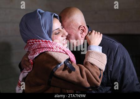 (231129) -- GAZA, 29. November 2023 (Xinhua) -- Ein freigelassener palästinensischer Gefangener (L) vereinigt sich mit einem Familienmitglied im Dorf Dura, südlich der Westjordanstadt Hebron, 29. November 2023. Die israelische Regierung bestätigte am Dienstag, dass die fünfte Reihe von Geiseln, die von der Hamas aus dem Gazastreifen entlassen wurden, nach Israel zurückgekehrt ist. Die 12 Geiseln, darunter 10 Israelis und zwei thailändische Staatsangehörige, werden einer ersten medizinischen Untersuchung unterzogen, bevor sie von Sicherheitskräften in das Krankenhaus gebracht werden, wo sie mit ihren Familien wieder zusammengeführt werden, so die Erklärungen des Büros des israelischen Premierministers an Stockfoto