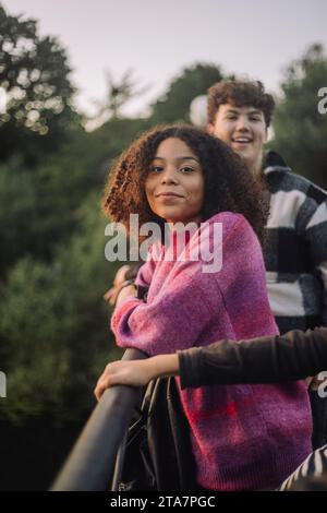 Seitliches Porträt eines lächelnden Mädchens, das auf Geländer gelehnt ist Stockfoto