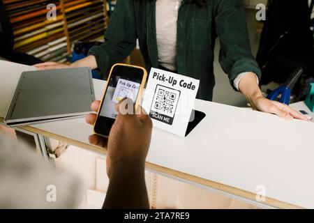 Hochwinkelansicht des Mannes, der Barcode während der Online-Zahlung in der Werkstatt scannt Stockfoto