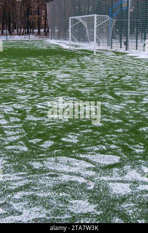 Fußballfeld im Winter, künstliches Gras auf freiem Schnee im Ferntor und Netz. Stockfoto