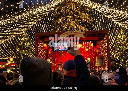 Bühne auf dem Weihnachtsmarkt am Roncalliplatz vor dem Dom, Mann fotografiert mit seinem Smartphone, Köln, Deutschland. Buehne auf dem We Stockfoto