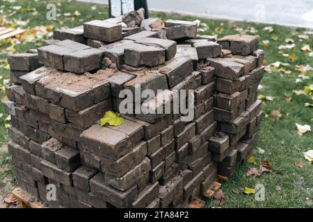 Rostig und verrostet ein Haufen verwitterter und rostiger Pflasterplatten, die während der Renovierung der Straße aufgestapelt wurden und Anzeichen von Abnutzung zeigen, mit Rissen und Spuren Stockfoto