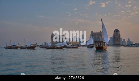 Katara13th traditionelles Dhow-Festival in Doha Katar Sonnenuntergang mit traditionellen Daus im arabischen Golf mit Fahnen der teilnehmenden Länder. Stockfoto