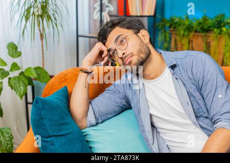 Porträt eines traurigen indischen Hindu-Mannes, der zu Hause sitzt, sieht nachdenklich aus, denkt über Lebensfragen oder unerwiderte Liebe nach, leidet unter unfairer Situation. Problem, Schluss, depressiv, genervt, Burnout Stockfoto