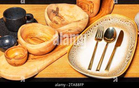 Wunderschöne Töpferwaren, handgefertigte Holzschalen, leere Keramikplatten und Tassen auf einem Holzständer. Stockfoto