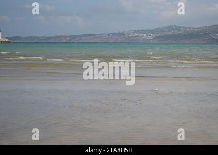 Nicht bearbeitetes Foto von friedlichem Wasserhorizont und Sandzusammensetzung. Nützlicher Sommerhintergrund mit Sandstrand mit Wasserrand Stockfoto