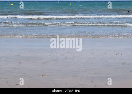 Nicht bearbeitetes Foto von friedlichem Wasserhorizont und Sandzusammensetzung. Nützlicher Sommerhintergrund mit Sandstrand mit Wasserrand Stockfoto