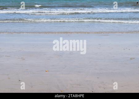 Nicht bearbeitetes Foto von friedlichem Wasserhorizont und Sandzusammensetzung. Nützlicher Sommerhintergrund mit Sandstrand mit Wasserrand Stockfoto