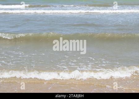 Nicht bearbeitetes Foto von friedlichem Wasserhorizont und Sandzusammensetzung. Nützlicher Sommerhintergrund mit Sandstrand mit Wasserrand Stockfoto