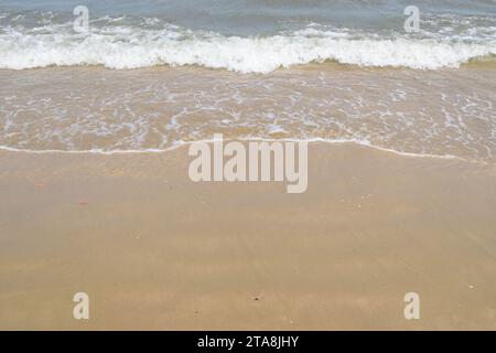 Nicht bearbeitetes Foto von friedlichem Wasserhorizont und Sandzusammensetzung. Nützlicher Sommerhintergrund mit Sandstrand mit Wasserrand Stockfoto